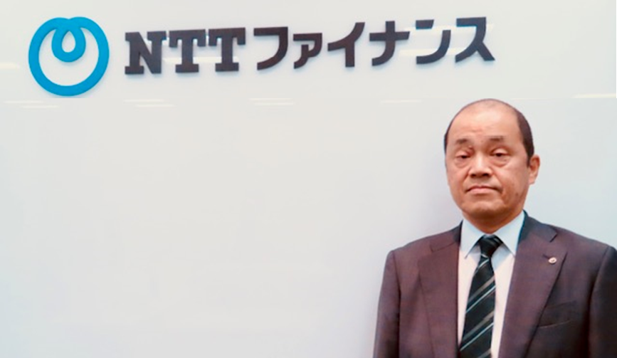 NTTファイナンスのロゴの前に立つ伊藤 正三代表取締役社長